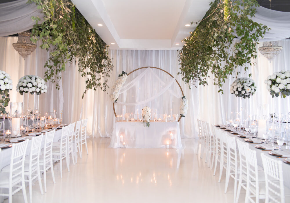 Interior of modern wedding venue with gold chandeliers and white draped ceilings