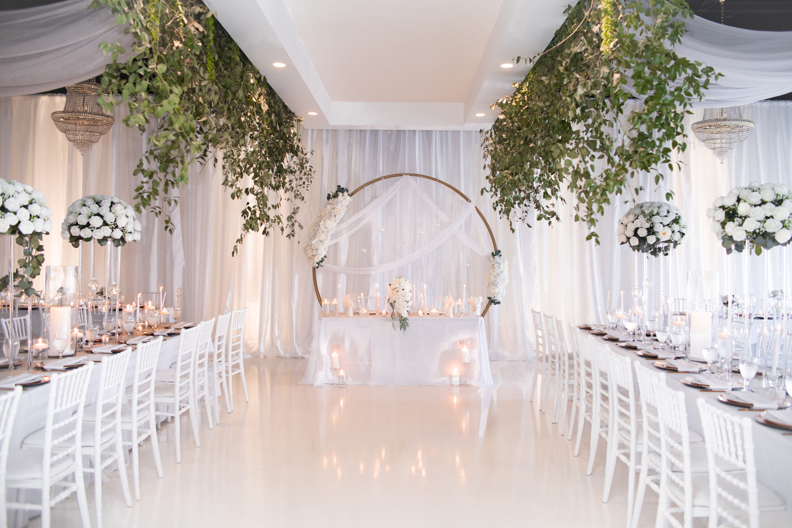 Interior of modern wedding venue with gold chandeliers and white draped ceilings